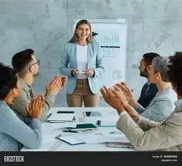 A group of professionals in an office setting clapping for a SMM expert standing in front of a whiteboard with charts. Best freelance digital marketing analyst in calicut.